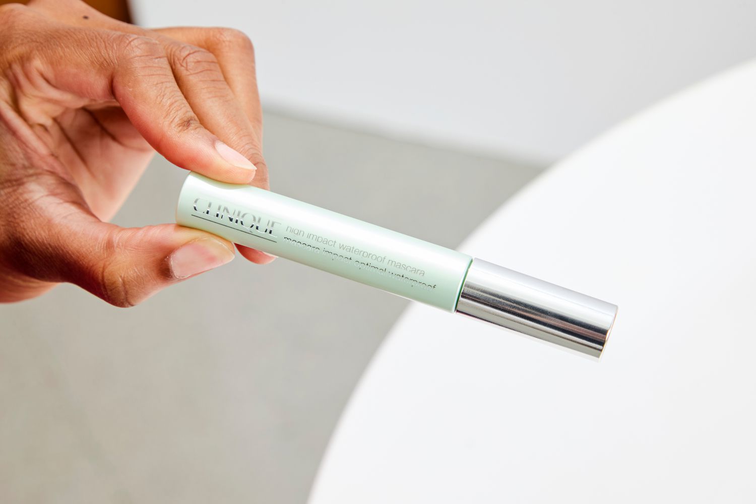 A person holds up a tube of Clinique High Impact Waterproof Mascara