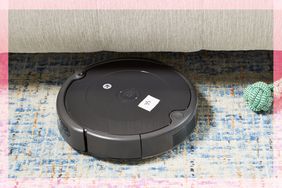 iRobot Roomba 694 Robot Vacuum on a rug going under couch next to a dog toy