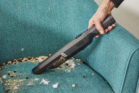 hand cleans crumbs off chair with Shark WANDVAC Cordless Hand Vac WV201