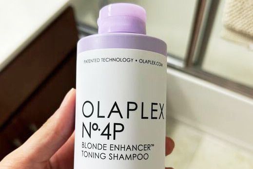 Closeup of hand holding Olaplex No.4P Blonde Enhancer Toning Shampoo