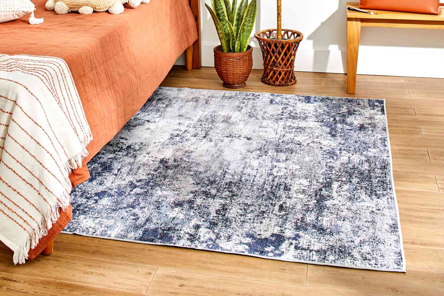 The Better Homes & Gardens Abstract Machine Washable Area Rug in a bedroom setting