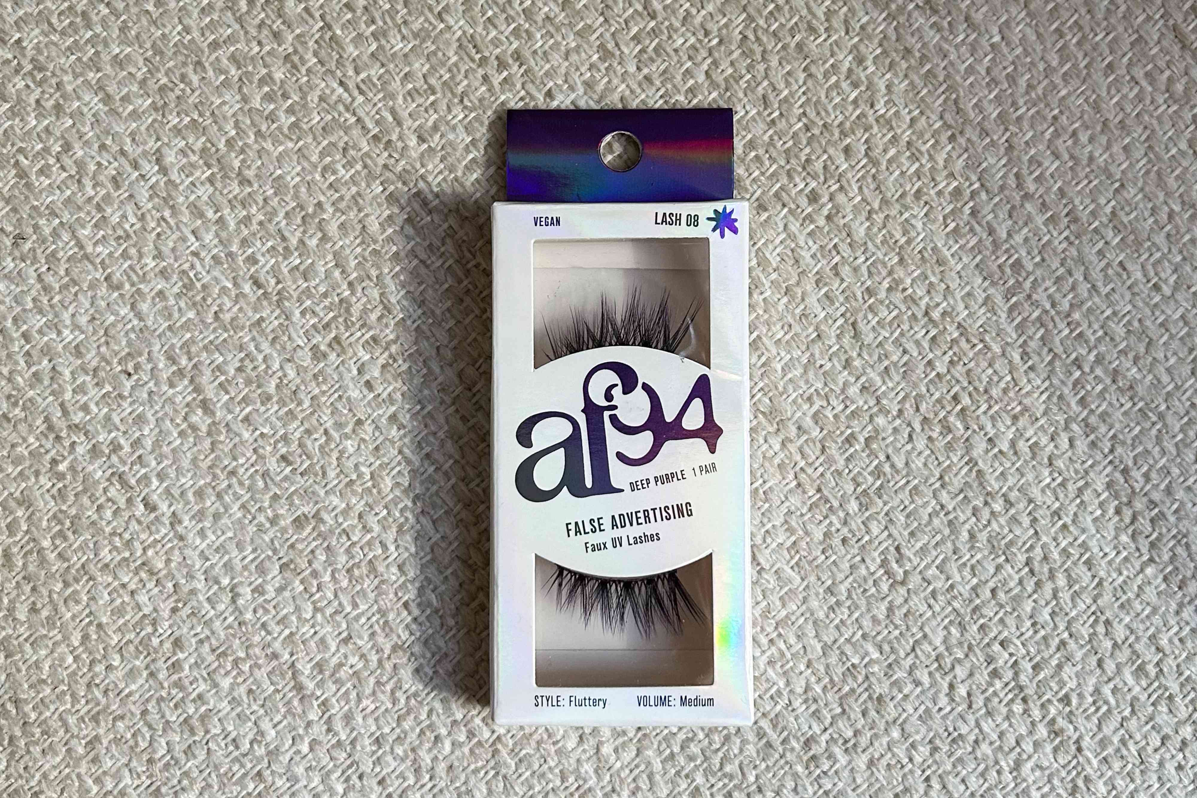 AF94 Deep Purple False Advertising Faux UV Lashes on a flat pattered surface