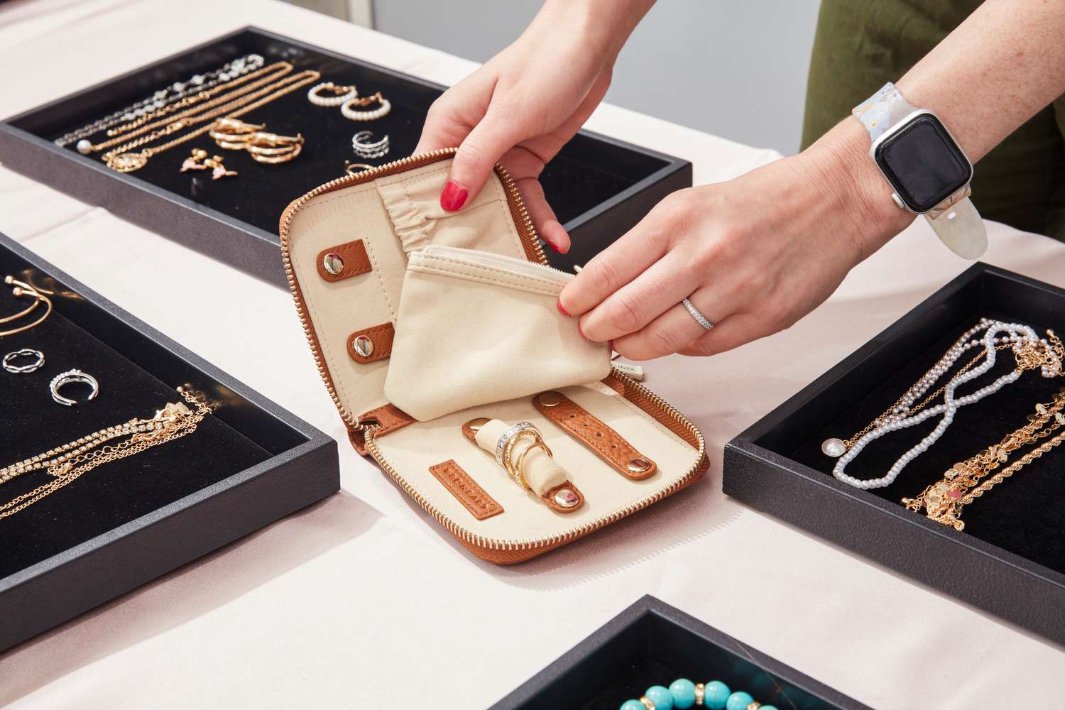 A person puts jewelry into the Levenger Carrie Mini Jewelry Organizer.