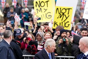 Demonstrators hold placards reading "Not My King" as Britain's King Charles III (C) meets well-wishers upon arriving at the Church of Christ the Cornerstone in Milton Keynes, north of London on February 16, 2023, to attend a reception to mark Milton Keynes' new status as a city.