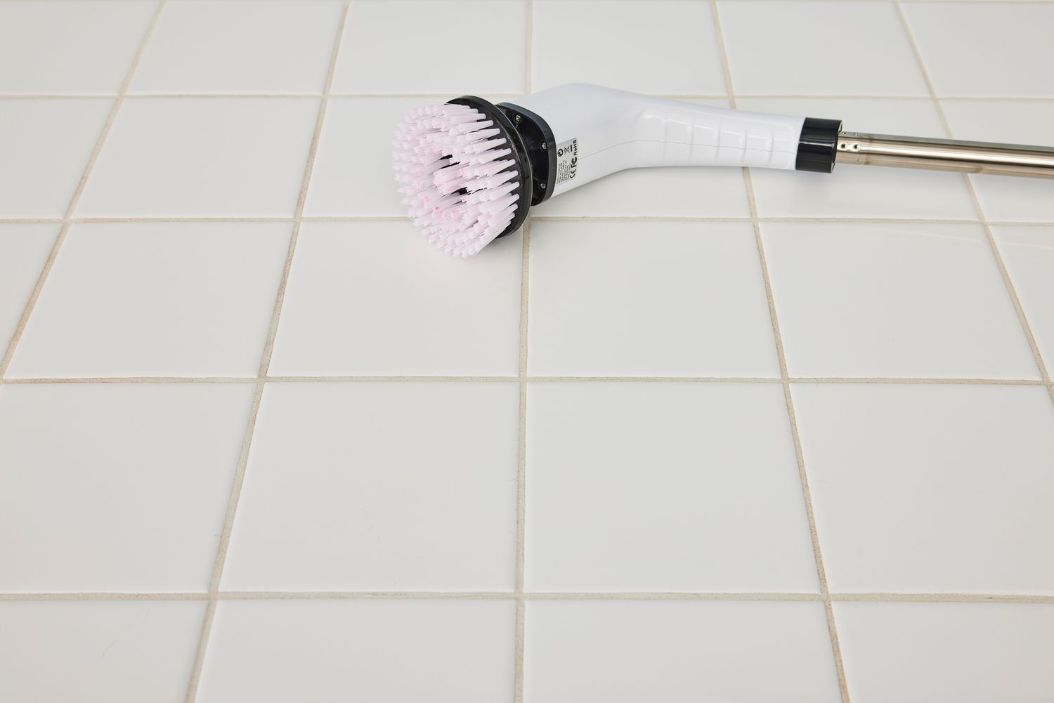 A Losuy Electric Spin Scrubber lying on its side on white tile