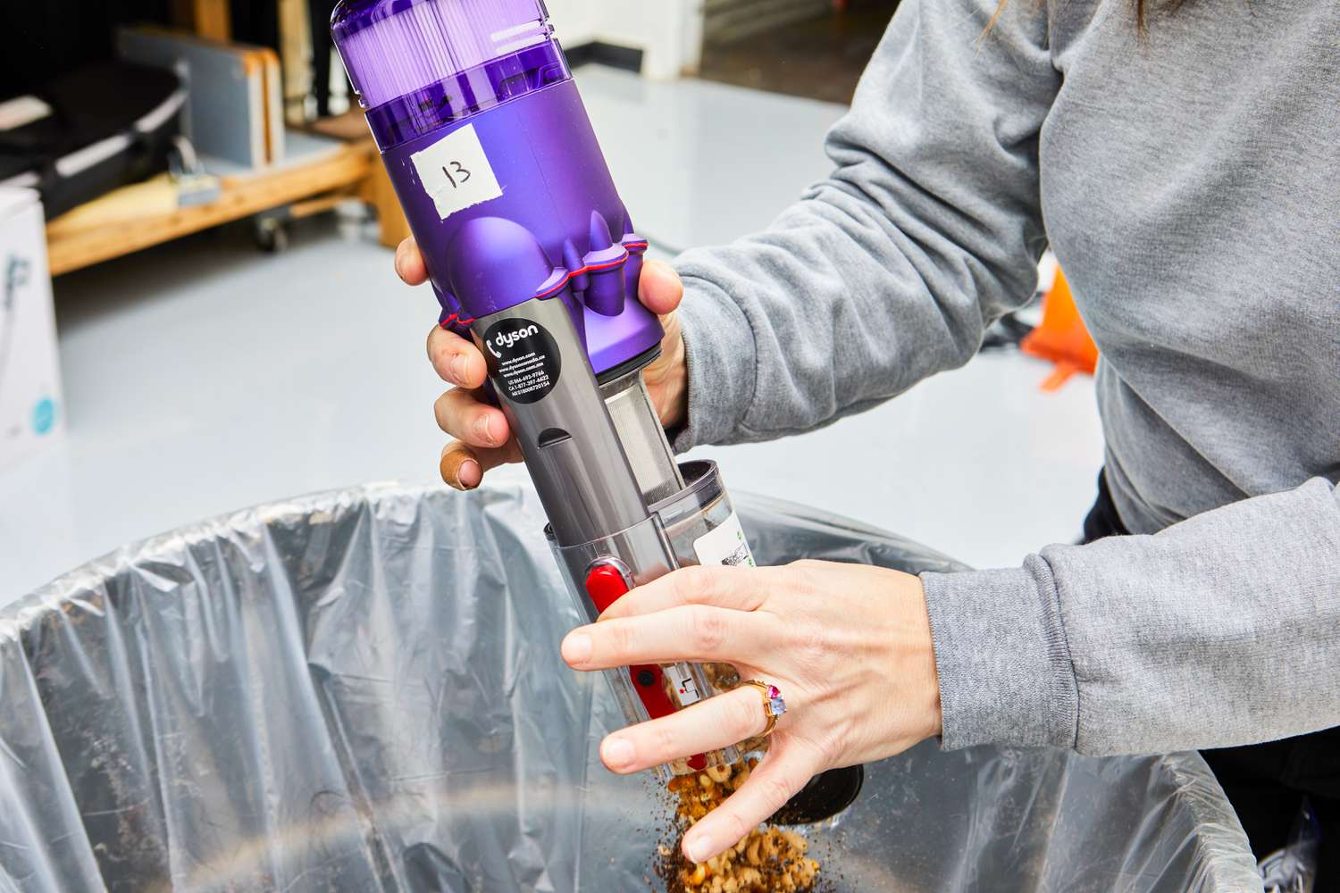 A person emptying the Dyson Omni-Glide+ Cordless Vacuum in the trash