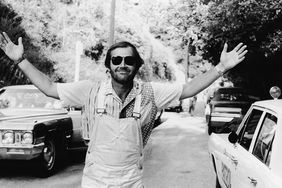 American actor Jack Nicholson smiles with his arms outstretched, wearing overalls and sunglasses, while attending the Motion Picture Relief Fund Auction at Columbia Ranch, California, June 4, 1972.