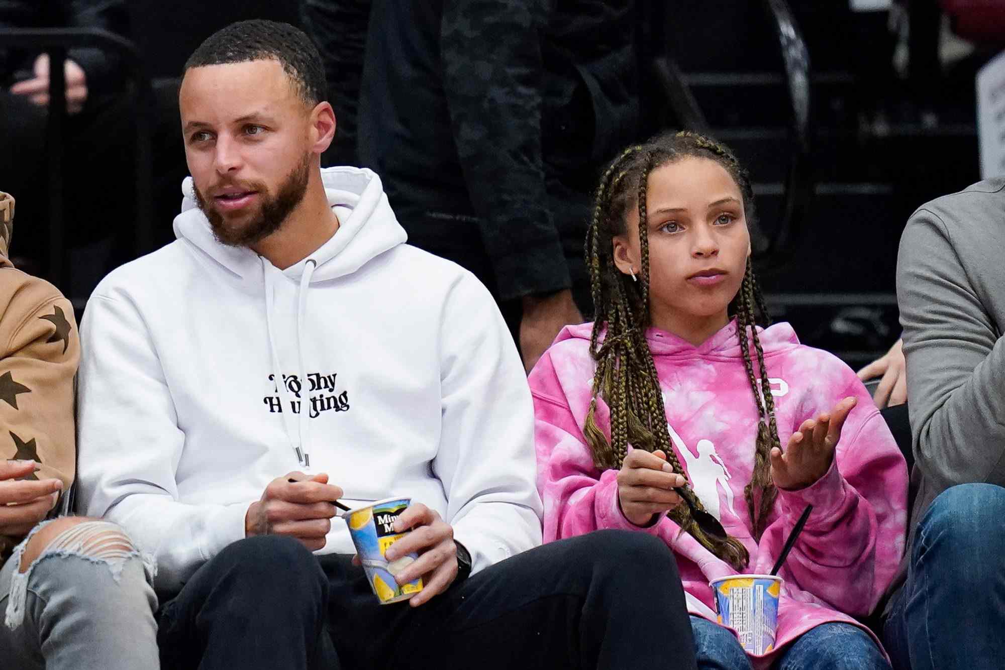 Trey Lance, second from left, talks with Stephen Curry, right, while sitting courtside during the second half of an NCAA college basketball game between Stanford and Southern California in Stanford, Calif., Friday, Feb. 17, 2023. (AP Photo/Godofredo A. Vásquez)