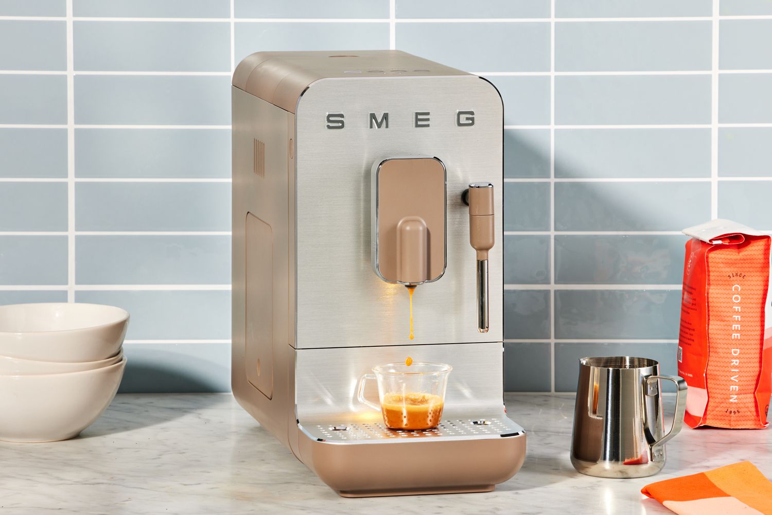 The SMEG Medium Fully-Automatic Coffee Machine on a kitchen counter next to coffee beans.
