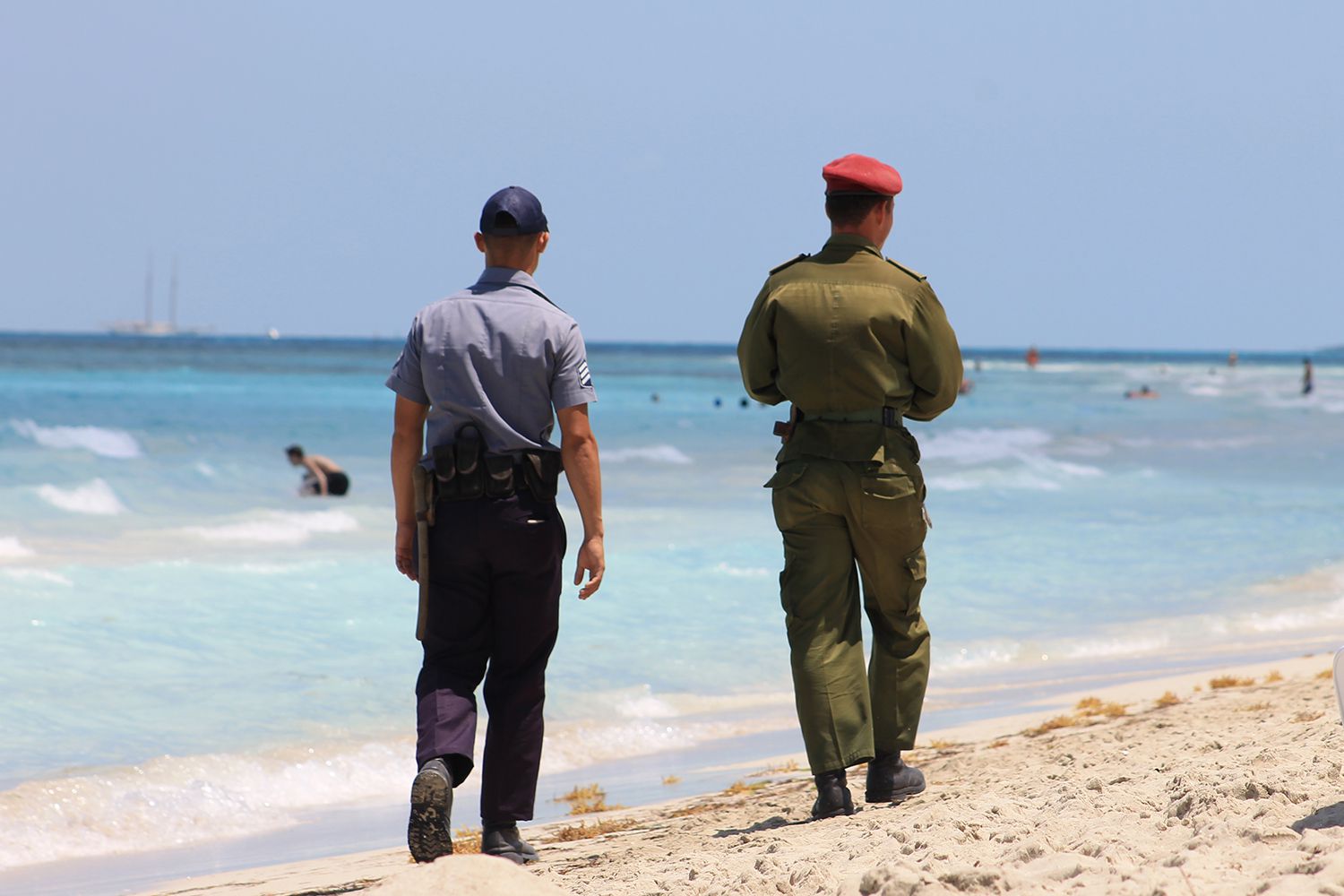 A Cuban soldier and a Cuban police officer walk along the beach together on Varadero Beach, Varadero, Cuba.