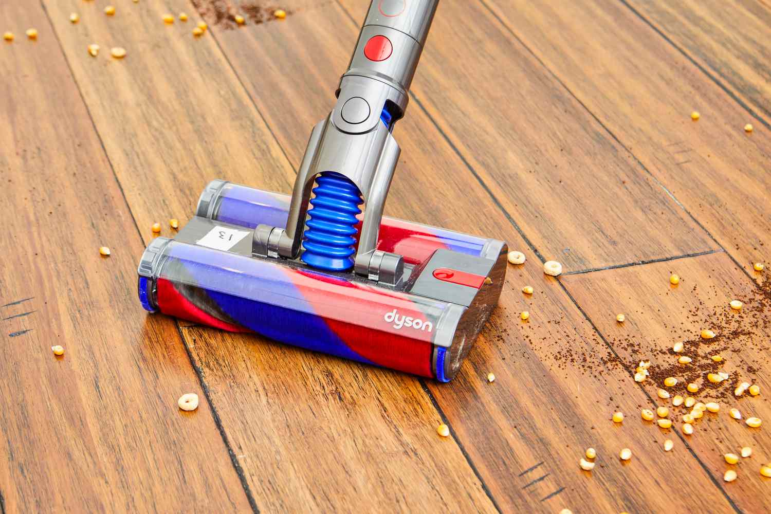 Closeup of the Dyson Omni-Glide+ Cordless Vacuum cleaning food from wood floor