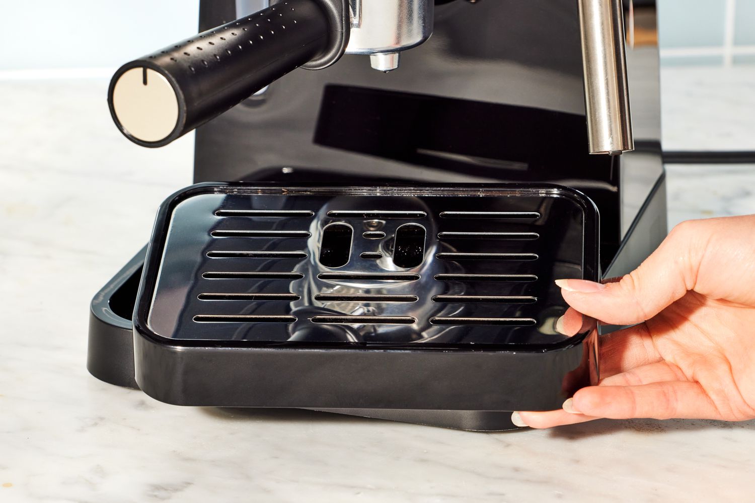 A hand holding the De'Longhi Stilosa Espresso Machine's drip tray.