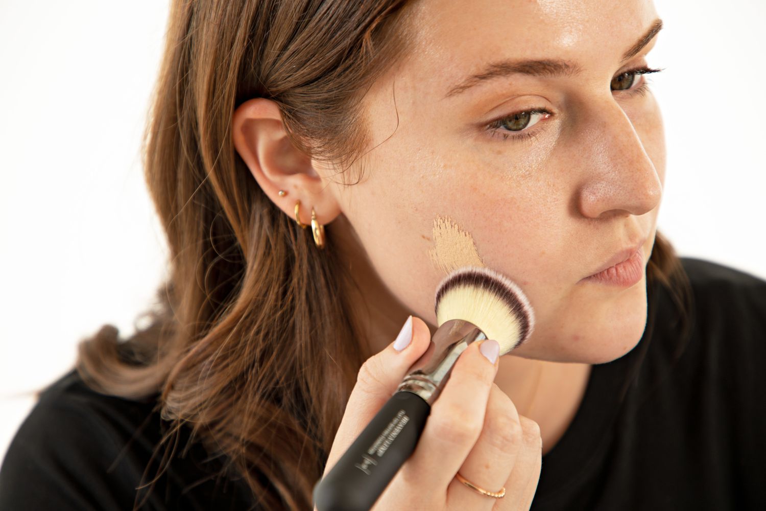 Person using a It Cosmetics Heavenly Luxe Flat Top Buffing Foundation Brush #6 to apply foundation to their cheek