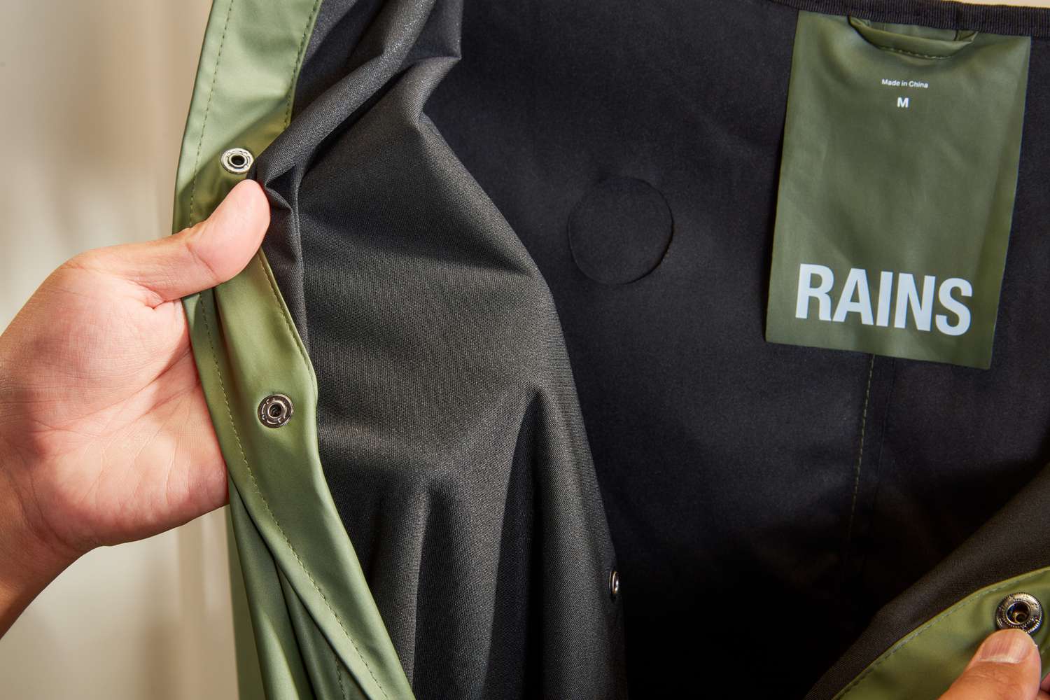 Person holding the inside of a Rains Men's Long Jacket