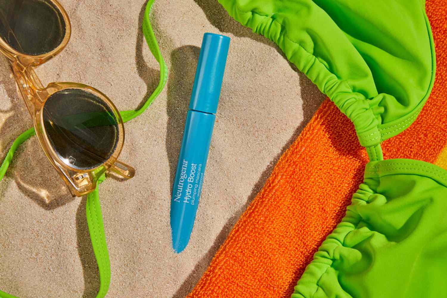 Neutrogena Hydro Boost Plumping Mascara Tested sits in sand with bikini top and sunglasses