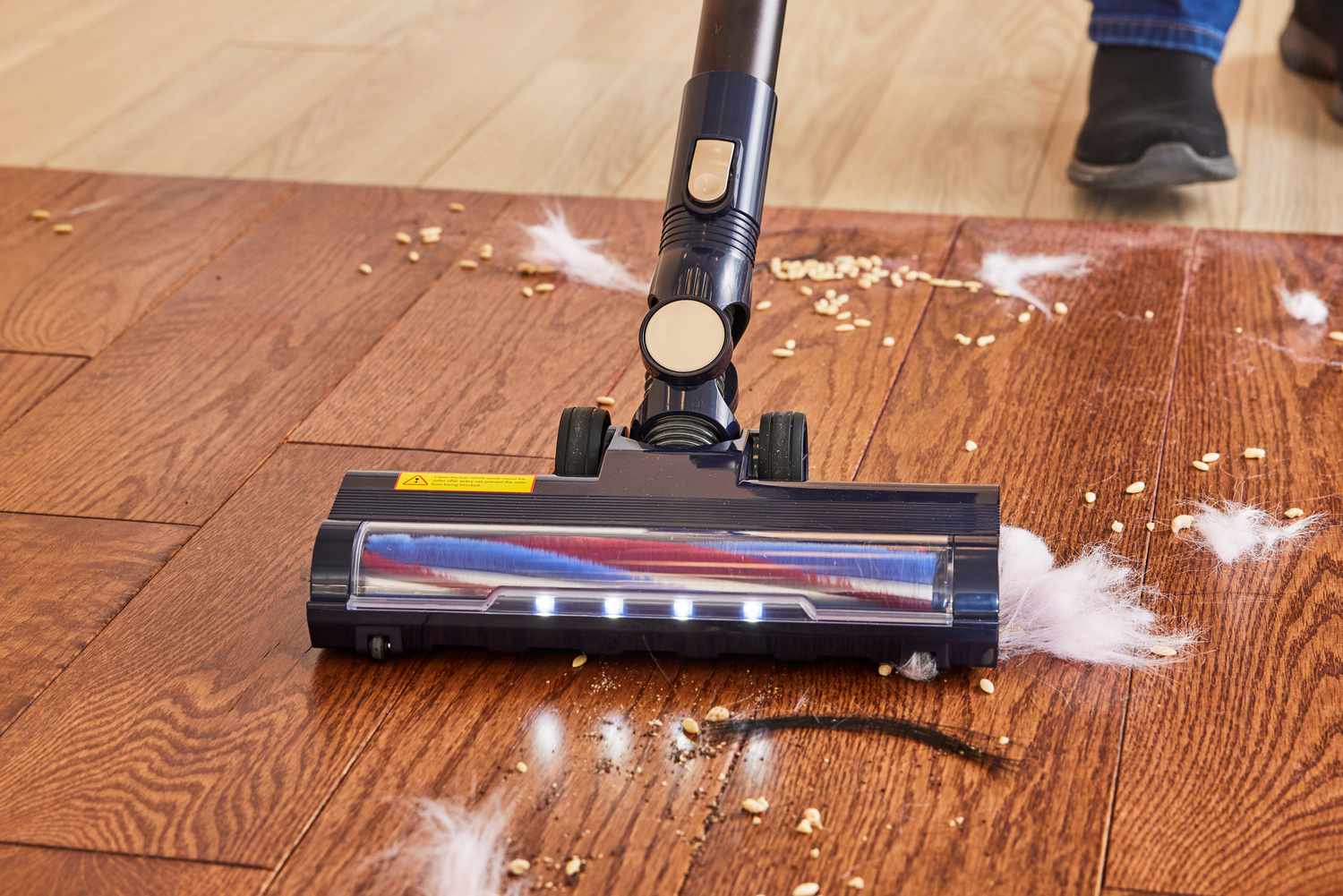 The Homeika Cordless Vacuum cleaning a mess on a wooden floor