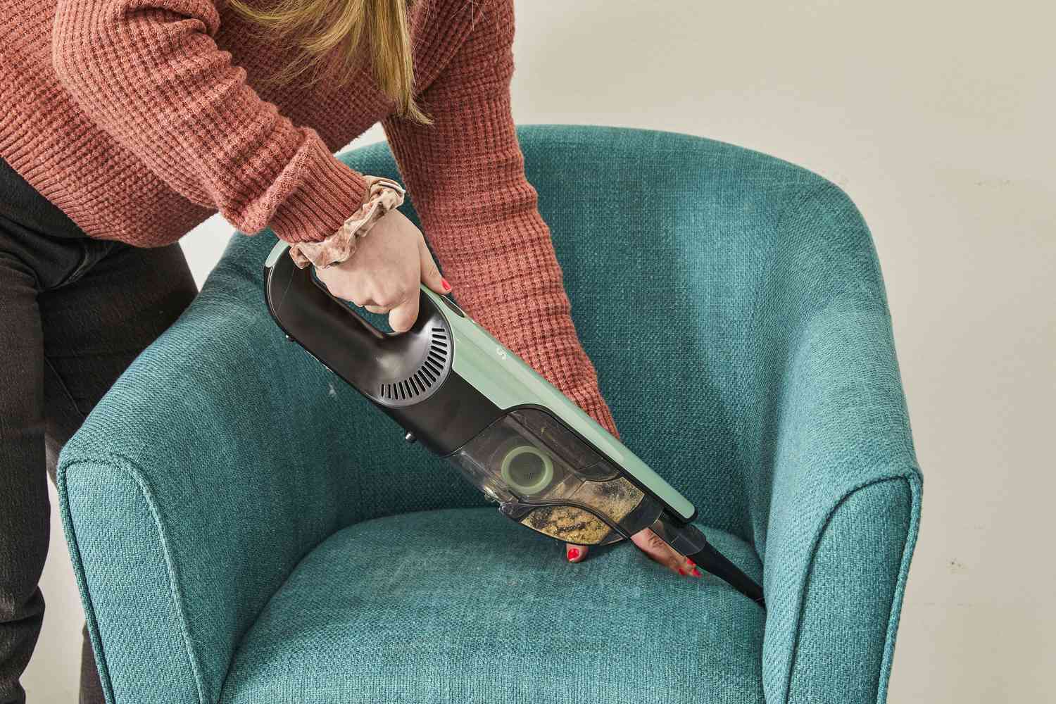 Person using Shark UltraCyclone Pro Cordless Handheld Vacuum to clean corners of chair