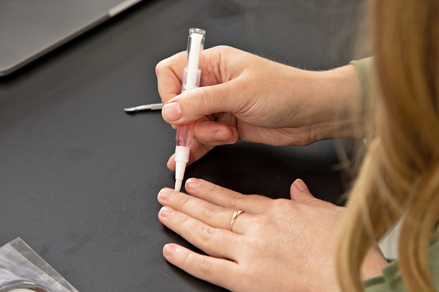 Close up of hands using Gellen Gel Nail Polish Kit cuticle oil pen