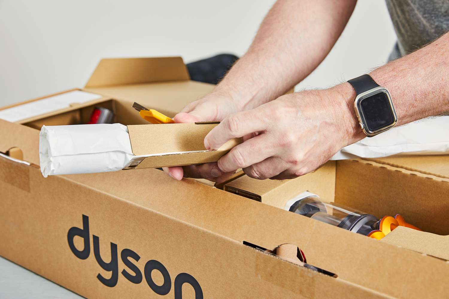 A hand removing cardboard covers off a Dyson V12 Detect Slim part