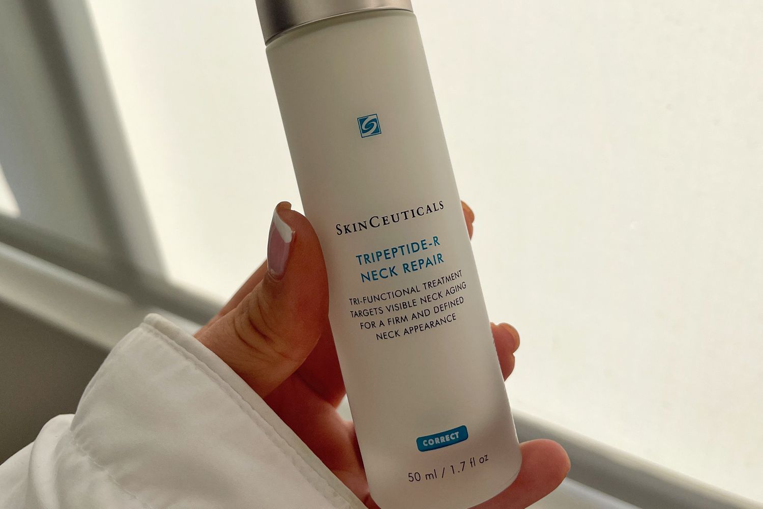 A person holds up a jar of SkinCeuticals Tripeptide-R Neck Repair
