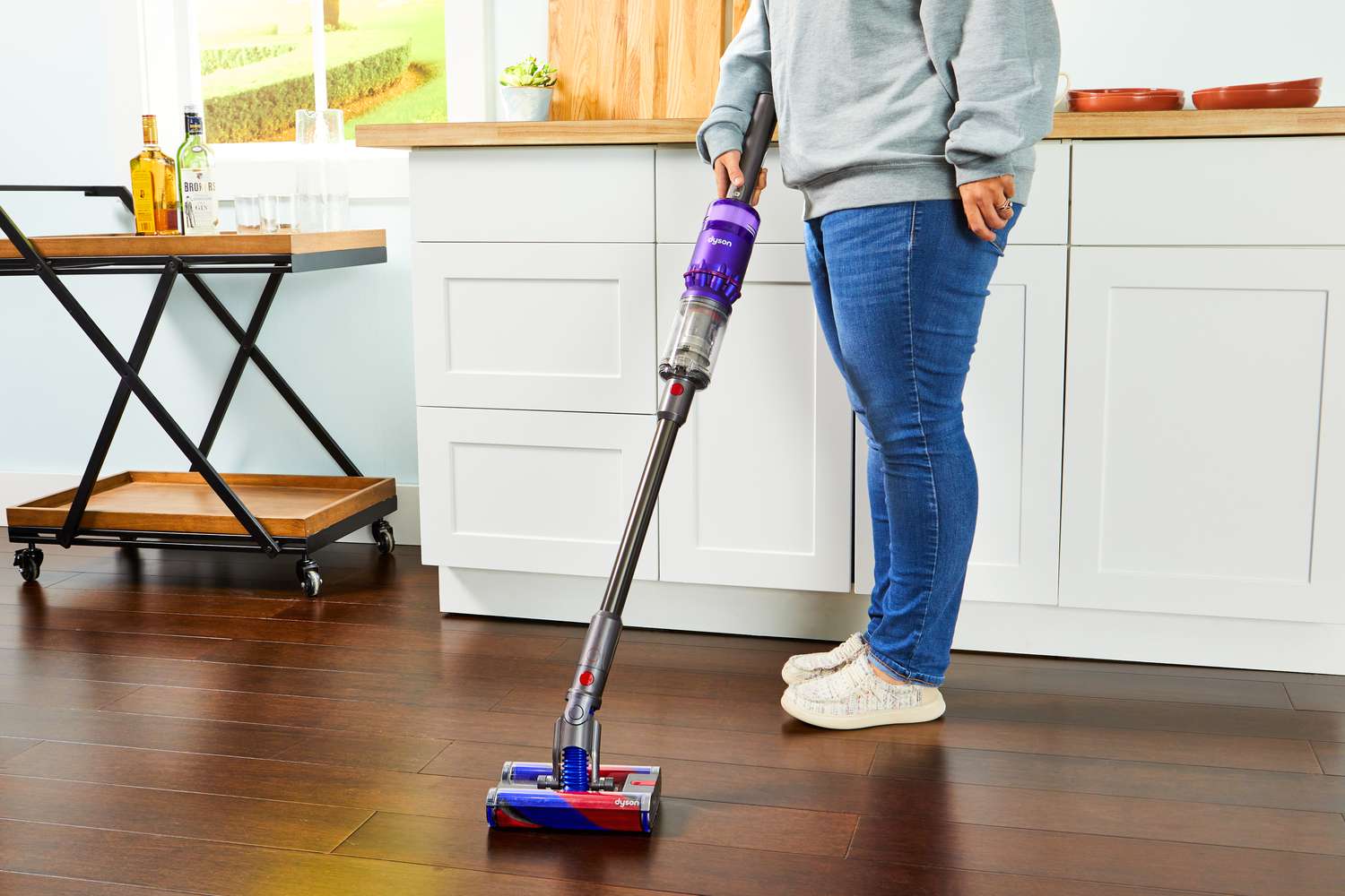 A person using a Dyson Omni-Glide+ Cordless Vacuum to clean the hardwood floor