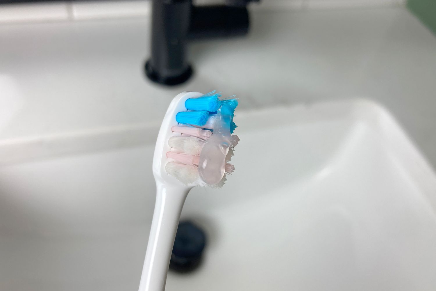 A toothbrush with a dot of HiSmile Everyday SmileCare hovering over a sink