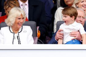 Camilla, Duchess of Cornwall looks on as Prince Louis of Cambridge sits on his grandfather Prince Charles, Prince of Wales's lap as they attend the Platinum Pageant on The Mall on June 5, 2022