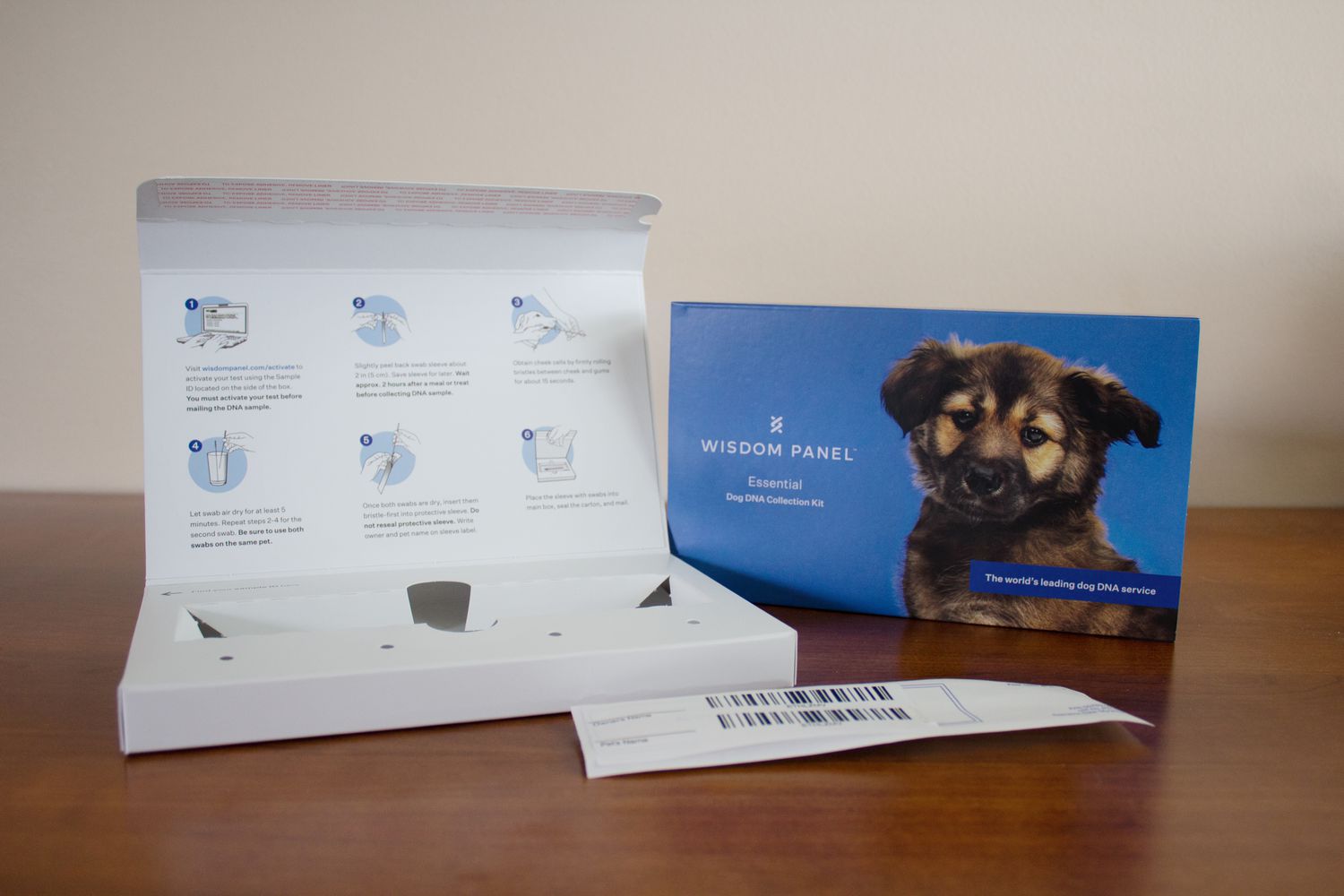 Instructions for a Wisdom Panel Essential Dog DNA Collection Kit displayed on a wooden table
