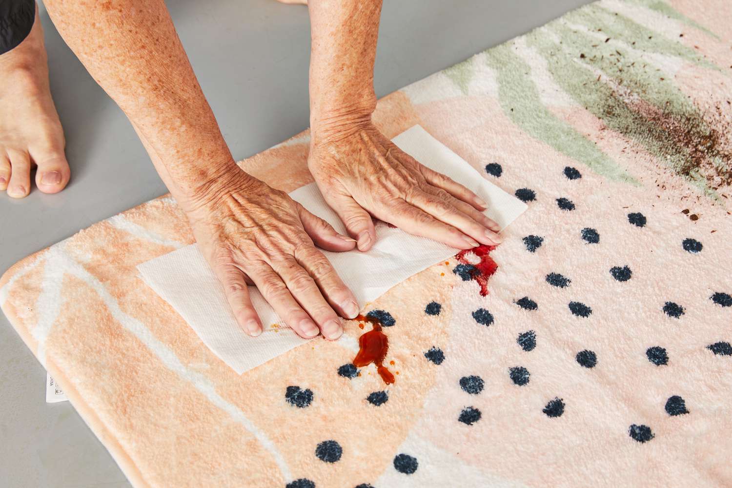 A person cleaning a stain on Lahome Washable Area Rug with a paper towel
