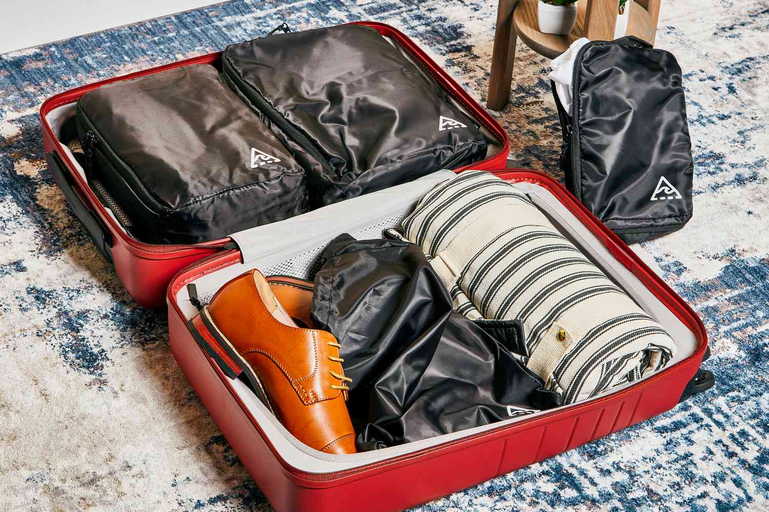 Well Traveled Compression Packing Cubes inside red suitcase sitting on blue and white carpet