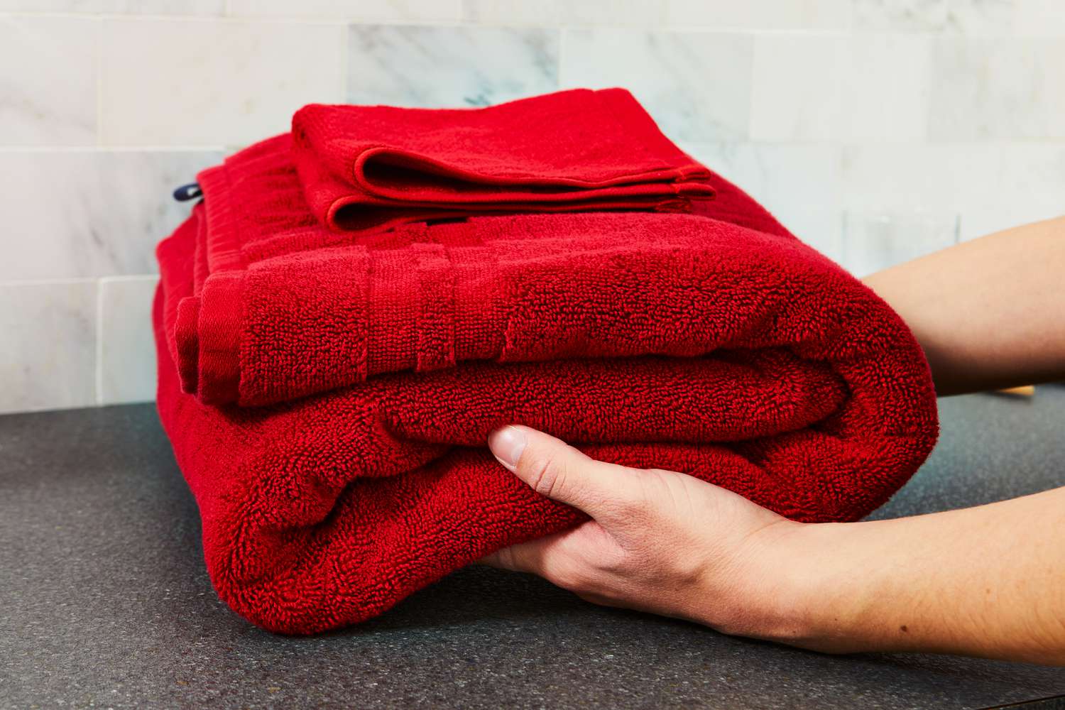 Person grabbing folded stack of Ralph Lauren Payton Towel Collection towels 