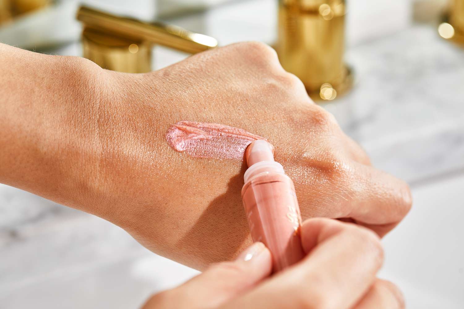 A person applying Lancome Juicy Tubes Lip Gloss to the back of their hand