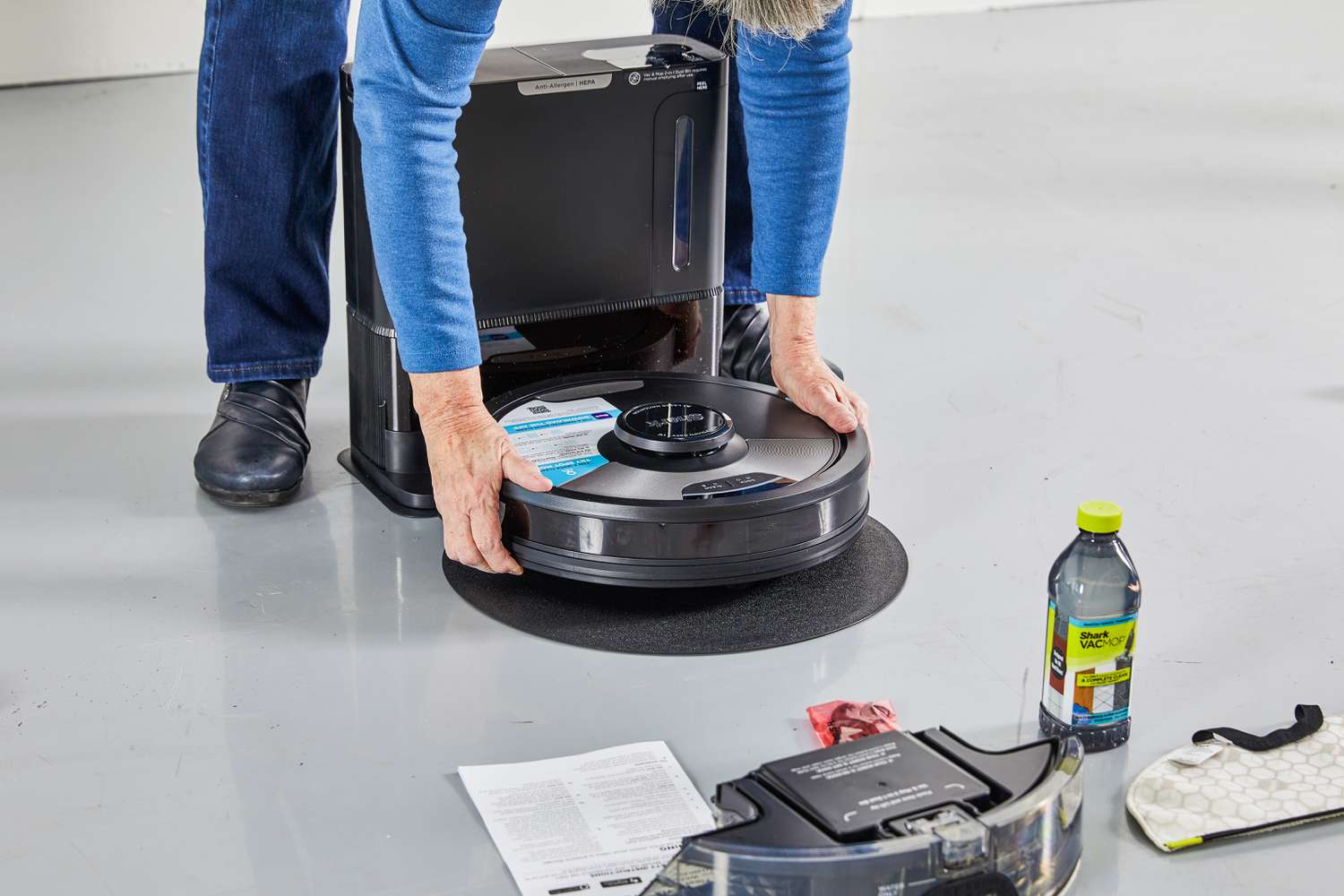 Person assembling the Shark AI Ultra 2-in-1 Robot Vacuum & Mop on its base on the floor 