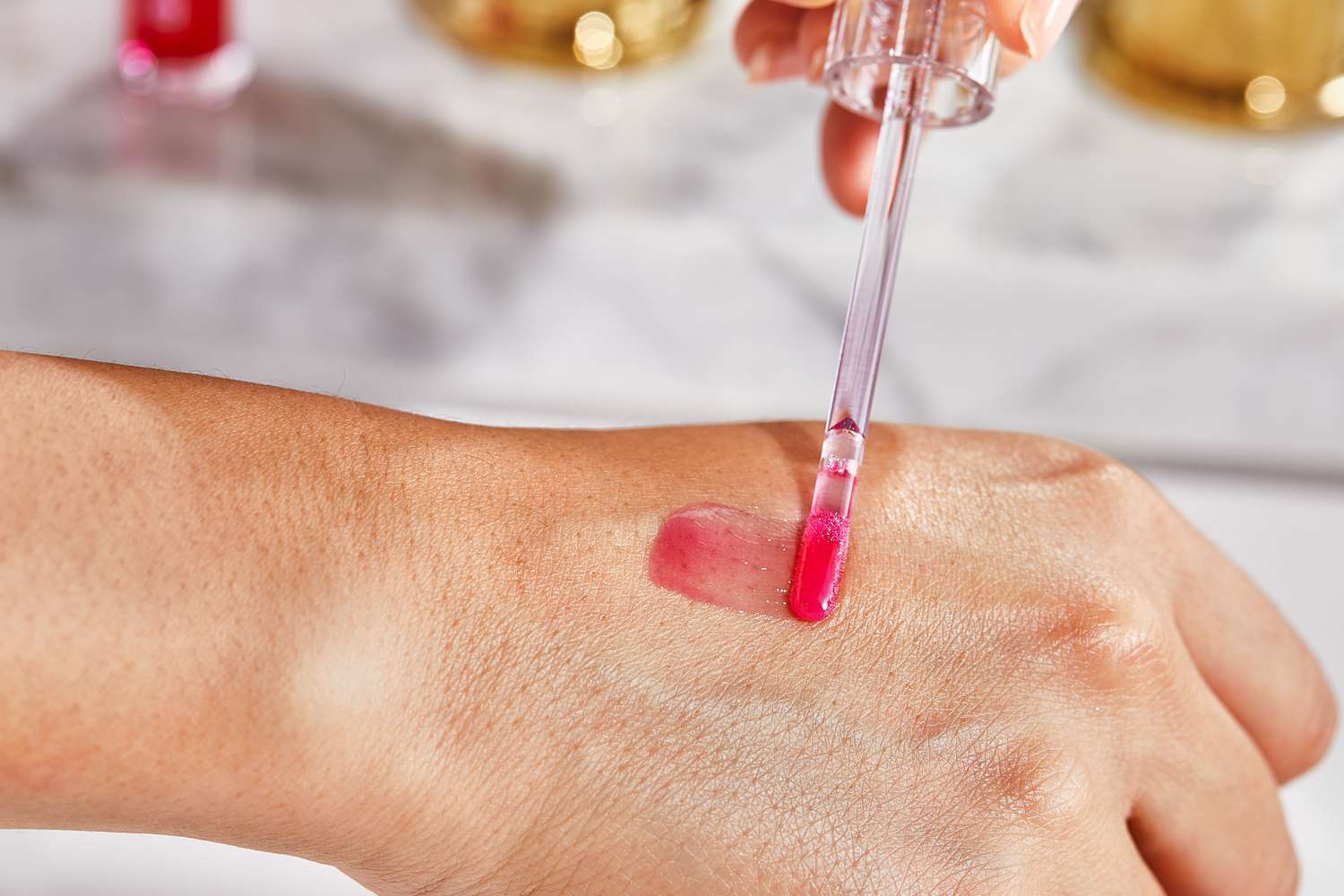 Close up of a person applying Tower 28 ShineOn Lip Jelly Non-Sticky Gloss to the back of their hand