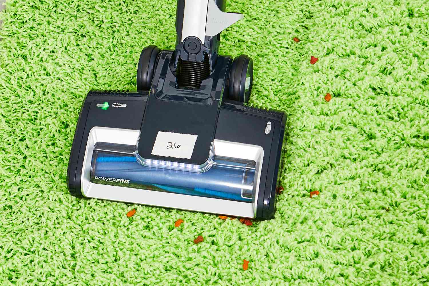 Person cleaning dog food on a green carpet using the Shark Canister Pet Bagless Corded Vacuum