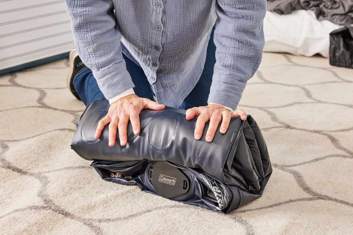 person rolls up Coleman SupportRest Double-High Rechargeable Air Mattress