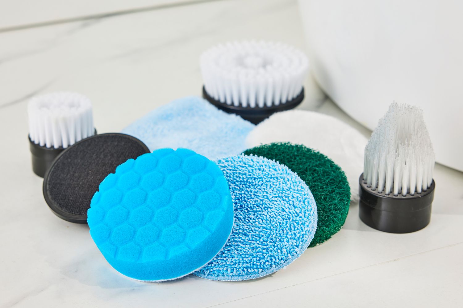 Various scrubbing pads for the Losuy Electric Spin Scrubber on a marble surface