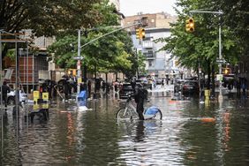 A man tries to pass a flooded street with his bicycle after a heavy rain in Williamsburg, New York, United States on September 29, 2023. 