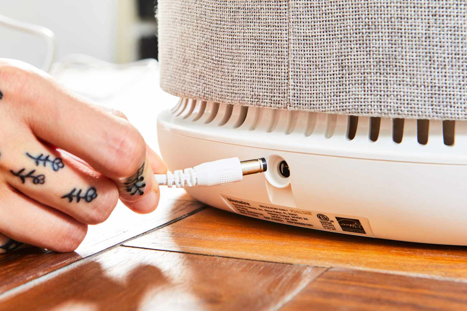 A person putting a plug into the Bionaire True HEPA 360Â° Air Purifier BAP0041UVWH
