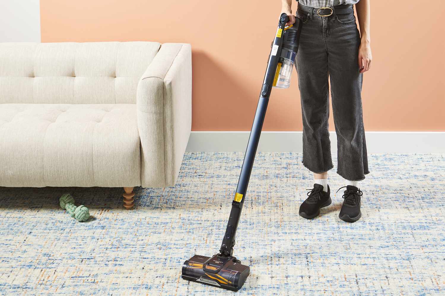Person using Shark Pet Pro Cordless Stick Vacuum Cleaner to clean dust on carpet