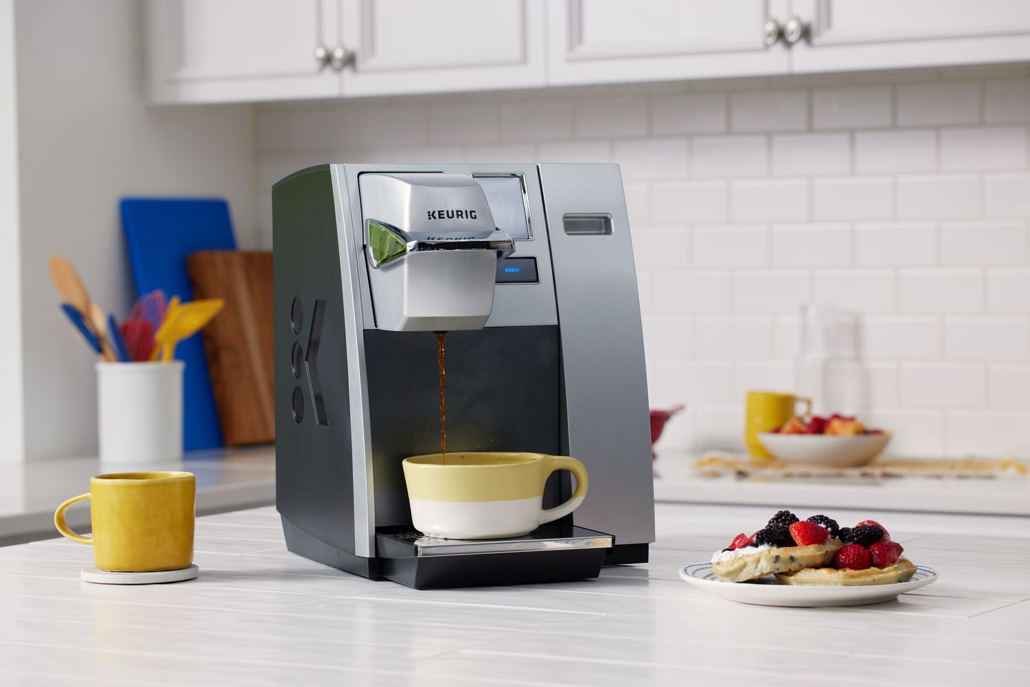 Keurig K155 OfficePro Premier Brewing System pouring coffee into a cup next to a plate of pancakes