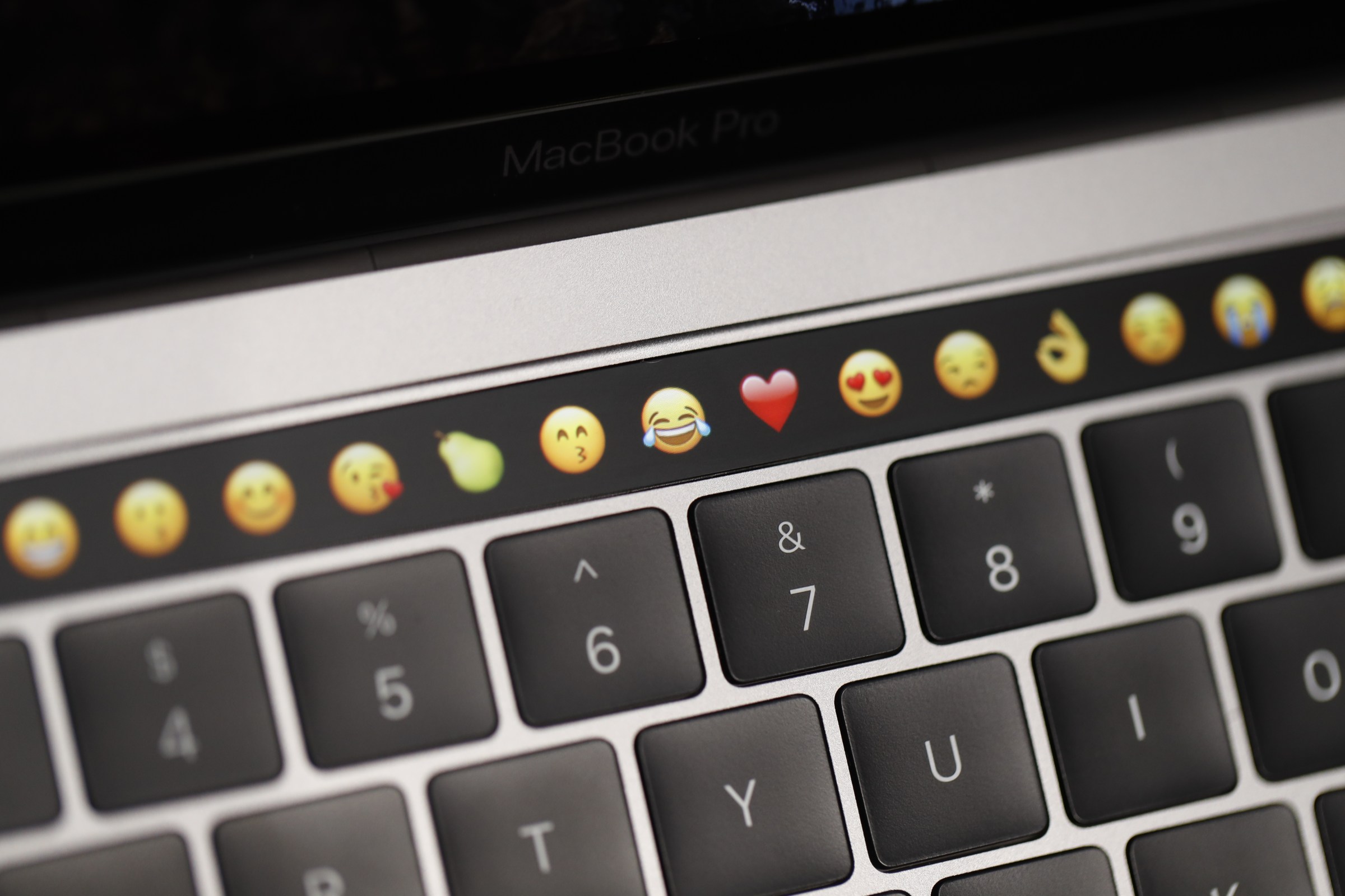 An Apple MacBook Pro’s task bar displaying emojis above its keyboard.