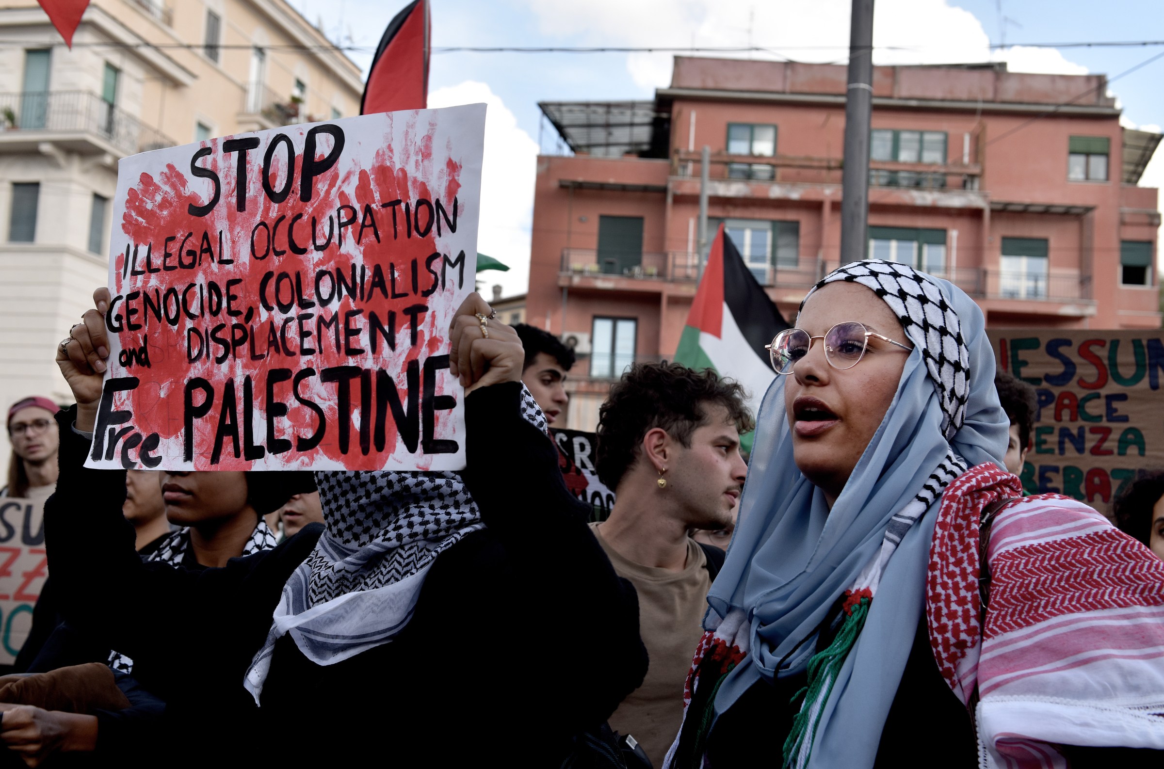 At a protest in Rome in October 2023 calling for a ceasefire and aid into Gaza, a protester holds a sign calling for an end to “colonialism and displacement” in Palestine.
