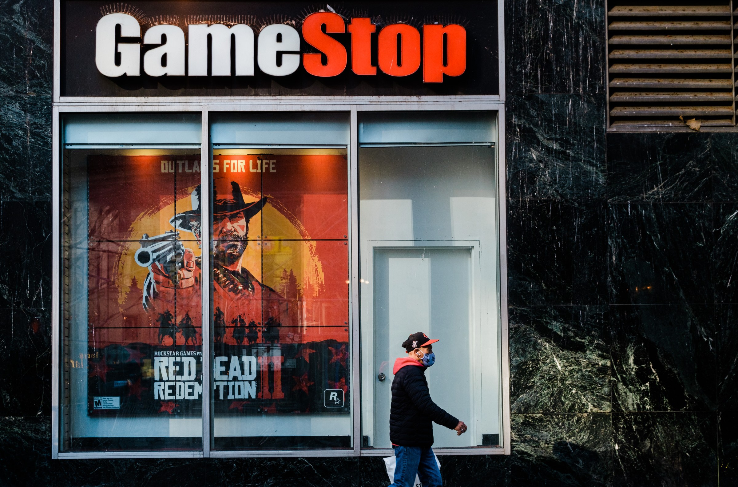 A pedestrian wearing a protective mask walks past a GameStop store in the Herald Square area of New York City on November 27, 2020.