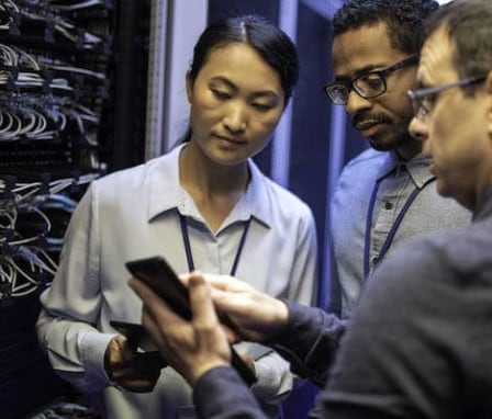 Three colleagues working together in computer server room