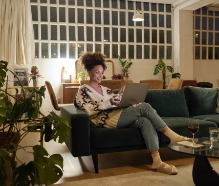 Woman typing on a laptop on her couch at home