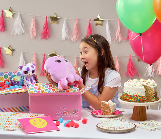 Young girl at a party table with balloons and party decorations opening gifts in birthday gift mailing supplies from pOpshelf.