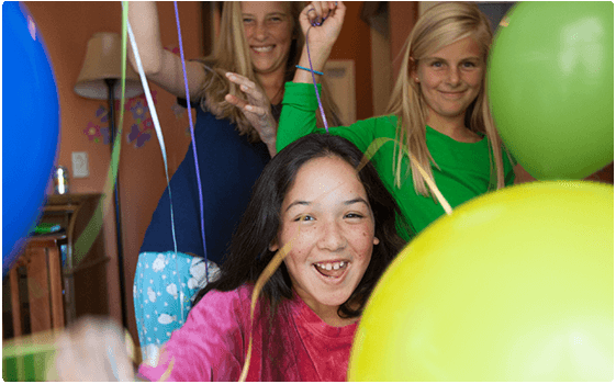 Three girls celebrating and laughing with balloons.