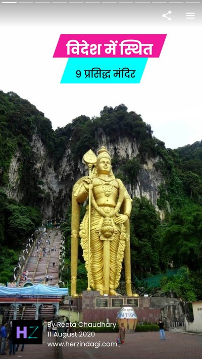 Large Hindi golden statue in front of a mountain covered in green foliage 