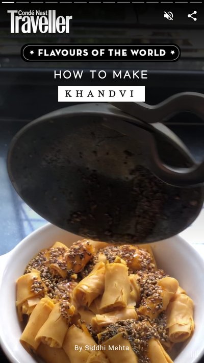 A pot containing Khandvi while having a suace poured on top